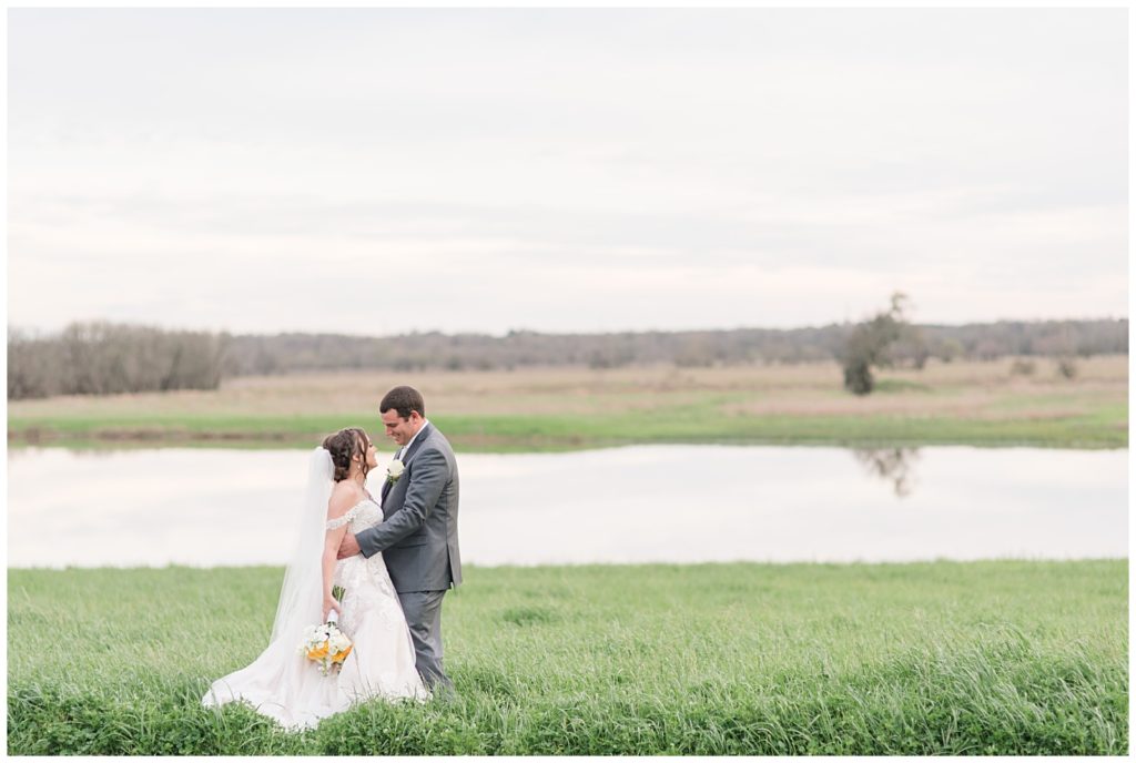 Lakefront Couple pose at Emery's Buffalo Creek | Yellow Farmhouse style Wedding 