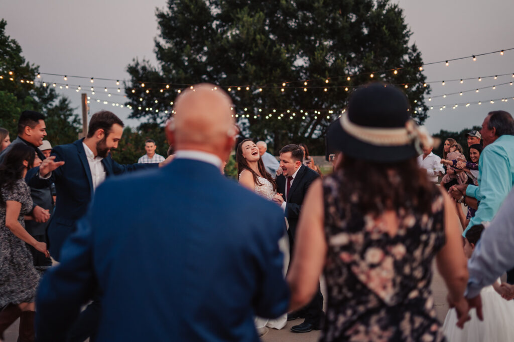 Photo of couple and guests dancing on the Emery's Buffalo Creek terrace at sunset
